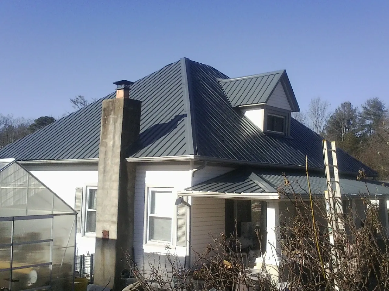 Dark blue standing seam metal roof on a white farmhouse with dormer — Slate & Tile Roof Repair by Roofing Brothers in Rockford