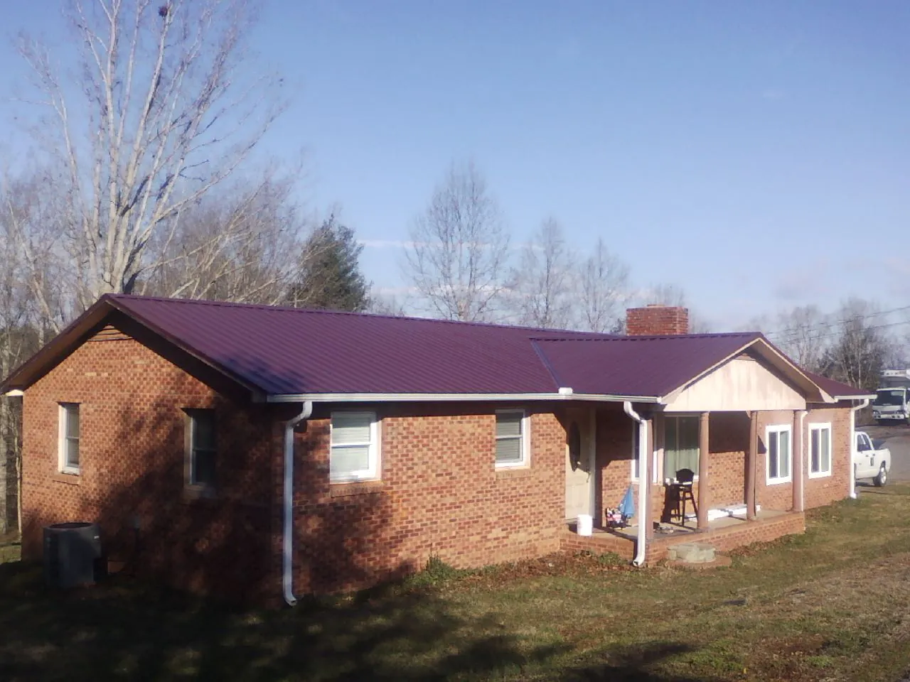 Burgundy metal roof on a brick ranch home with a new addition in Rockford